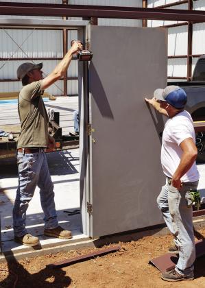 Dusty Heller, left, attaches the door to the frame of the new box hangar as Scott Oats helps keep the door in place Monday at Clinton Regional Airport. CDN | Christian Jacobsen