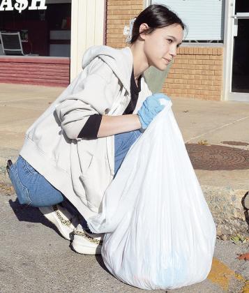 Senior Brylee Jones picks up trash left in the street as part of her Capstone community service on Frisco Avenue. CDN | Micah Ashcraft