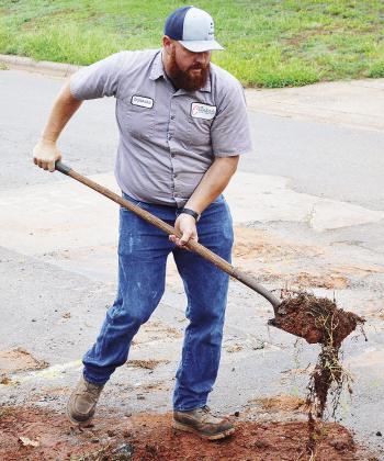 Donavan Phipps shovels debris away after clearing asphalt from a pipe under the road near the 1800 block of Opal Avenue. CDN | Micah Ashcraft