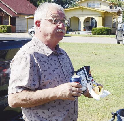 Troy Lee eats while he looks around during the cookout held by InterBank.