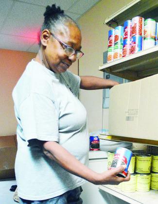 Betty Richardson helps stock the last of the available boxes of canned food donated to the food pantry at the Mission House. CDN | Micah Ashcraft
