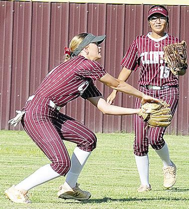 Clinton’s Stella Meacham, left, secures the ball in her glove with No. 15 Audrina Trout coming over for back up during the Lady Reds’ game against Bishop McGuiness. CDN | Sam Goodwyn