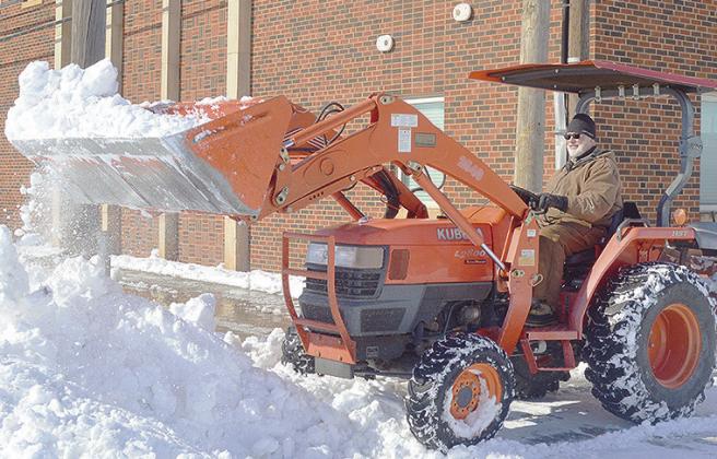 Joe Brown uses a small tractor to clear out the snow Monday morning from the parking area next to First Baptist Church. CDN | Micah Ashcraft
