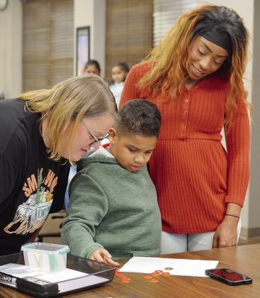 Nance Elementary School teacher Julie Adkinson, left, works on a lesson with her student Jordin Perez and his mother Carrie Perez during the Clinton Public Schools Board of Education’s monthly meeting Monday evening. CDN | Micah Ashcraft