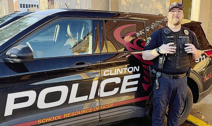 School Resource Officer Andrew Wilson stands with his patrol vehicle outside of the Clinton Police Department. CDN | Shiann Dawson