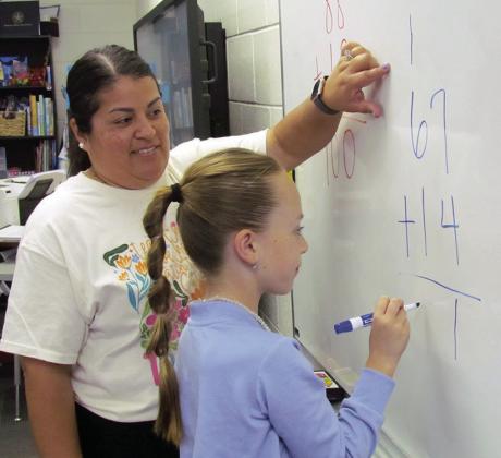 Brenda Martinez is helping Vivien Salinas carry the one in twodigit addition at Southwest Elementary School. CDN | Christian Jacobsen