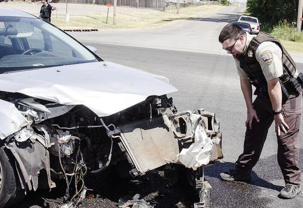 Custer County Sheriff Deputy Josh Thompson inspects the damage to a Ford Focus following a two-vehicle wreck which occurred just before 2:41 p.m. Wednesday on U.S. Highway 183 south of town near Giblet Stoves. The Focus and a BMW X5 were involved in the wreck. Emergency personnel said two people were reported to be injured in the wreck but refused treatment at the scene. CDN | Sam Goodwyn