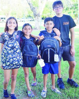 From left, Jayla Meraz, Giselle Torres, Brandon Torres, and Paulo Coutinho show off their new backpacks filled with school supplies given away by the Clinton Ministerial Alliance as part of its backpack drive Wednesday afternoon at McLain Rogers Park. CDN