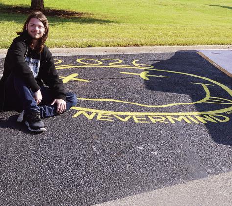 Nathan Savoie sits next to his Nirvana-inspired paint job for his personalized parking spot at Clinton High School. CDN | Micah Ashcraft