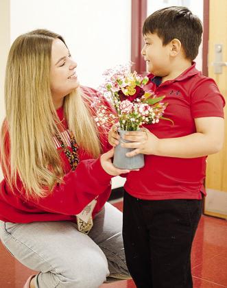 Teacher Libby Gregston, left, smiles as she is handed flowers from Jesus Martinez Friday morning at Nance Elementary. CDN | Sam Goodwyn