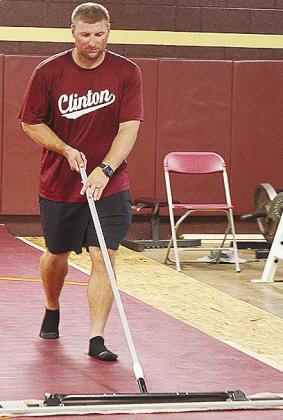 New Clinton High School wrestling coach Rhett Blundell sweeps the mats in the high school wrestling room Monday. CDN | Sam Goodwyn
