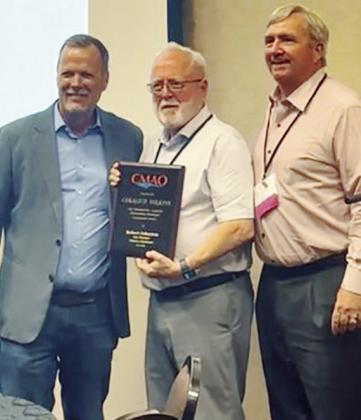Oklahoma Municipal Management Services Executive Director Steve Whitlock, left, Clinton City Manager Robert Johnston, and past President of the City Management Association of Oklahoma Brooks Mitchell stand together after presenting Johnston with the 2025 