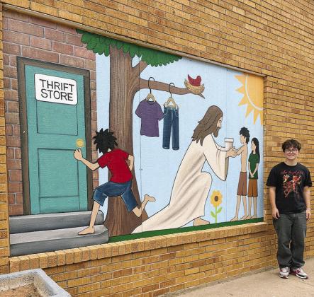 Micah Segler stands by the mural he designed and his fellow CHS art classmates painted outside the Twice is Nice thrift store at 113 S. 7th St. CDN | Courtesy photo