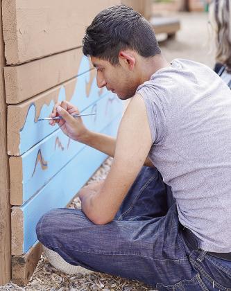 Demetrio Guzman splashes some detail onto some painted waves while painting with the Clinton High School Art Department at M.T. and Helen Gholston Children’s Park. CDN | Courtesy photo