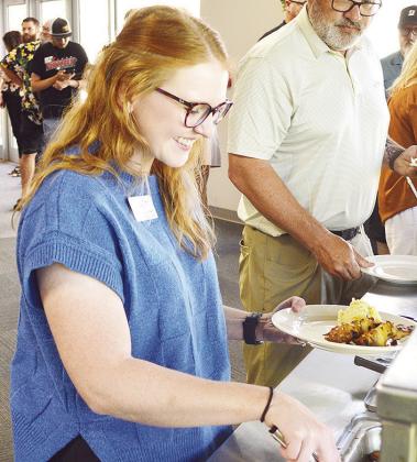 Burgundy Howes grabs a plate while at a Clinton Chamber of Commerce Luncheon recognizing new members held at the Frisco Center.