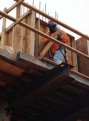 Gueybor “Jiro” Atilano Martinez removes wooden walls that held the form of freshly poured concrete on the Interstate 40 overpass support beam Tuesday at Neptune Drive. CDN | Christian Jacobsen