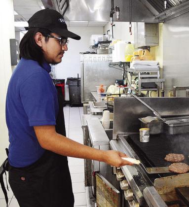 Julio Ramirez flips up some fresh patties behind the grill at Domino Fuel Stop off of U.S. Highway 183, just south of Clinton. CDN | Micah Ashcraft