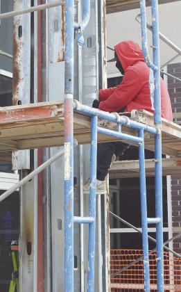 Edin Carrillo works to remove the rivets off the metal framework while repairing a pillar of the Clinton Public Library Wednesday morning, after a fire started within the pillar this past June. CDN | Micah Ashcraft