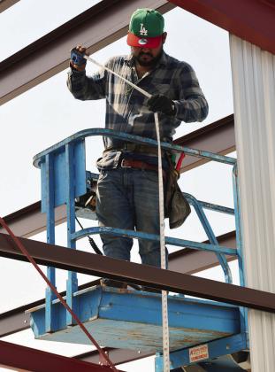 Jose Ayvar measures how tall a metal panel needs to be from floor to the roof of the new T-hangar being built at the Clinton Regional Airport. CDN | Christian Jacobsen