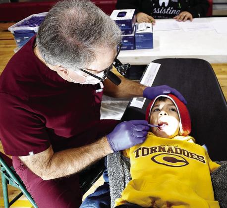 Dr. Floyd Simon Jr., left, takes a look inside the mouth of Nolan Amaya during the recent “Give Kids a Smile” event in conjuction with dental assisting students from Western Technology Center. CDN | Courtesy photo