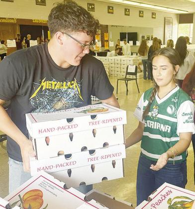 Layne Spitz, left, and Ali Fuentes unload pallets of boxed peaches to be sold as part of the Clinton High School Choir annual peach sale fundraiser at the Clinton High School Choir Room. CDN | Micah Ashcraft