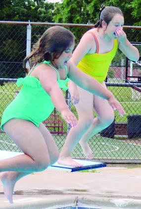 Tinlee Roper, left, and Bristol Miller jump together during Summer Playground at the Clinton Pool. CDN | Christian Jacobsen