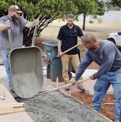 From left, James Holden, Parks Supt. Lyndon Perry, and Robert Plaza pour and level new concrete slabs for wheelchair access and usage Friday morning at the McLain Rogers Park Amphitheater. CDN | Christian Jacobsen