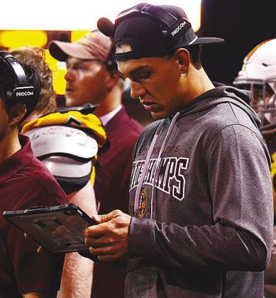 Former Clinton Red Tornado football player Caden Powell reads info off of a tablet Friday during Clinton’s homecoming game against Elgin. CDN | Micah Ashcraft