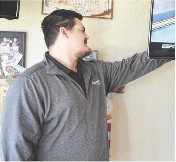 Wesley Flores helps set up the wired internet for the different TV displays at Adam’s Edge Barbershop. CDN | Micah Ashcraft