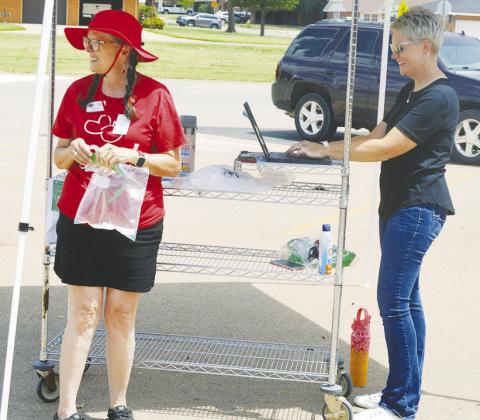 Leslie Lewis, left, and Natalie Blundell check in students getting take home meals from the summer program at Clinton High School. CDN | Christian Jacobsen