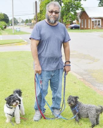 Jose Chavez walks his dogs Cujo and Mr. Mustard past the Clinton Post Office while visiting from Chicago to see family. CDN | Micah Ashcraft