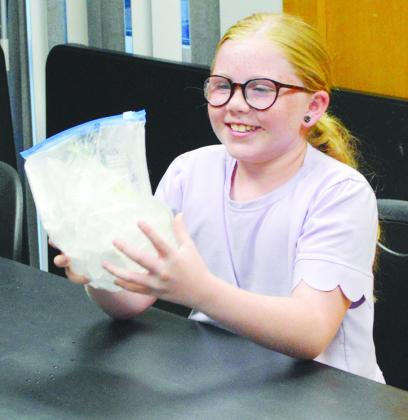 Joslynn Roll shakes a bag of cream and sugar with cold ice and salt to make soft-serve ice cream at the Clinton Library. CDN | Christian Jacobsen