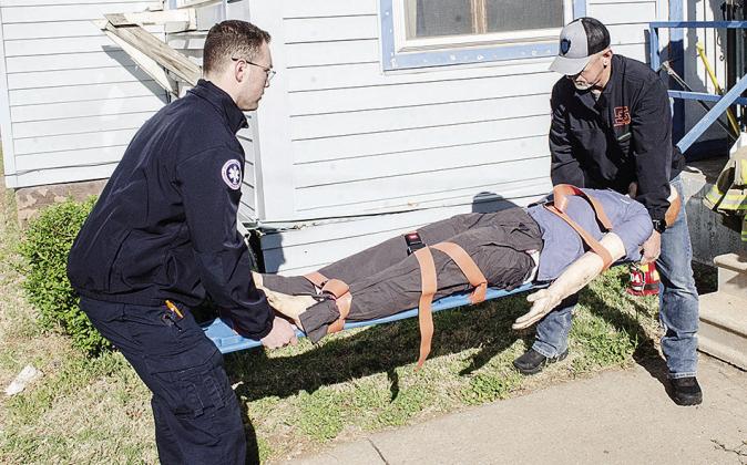 EMTs Christian Evans, left, and Jason Lambeth carry a medical dummy over to be used during training at the Mission House. CDN | Sam Goodwyn