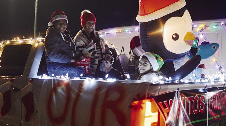 From left, Ana Sanchez, Lupe Marquez, and Jayla Meraz wave from the back of the Our Liquor Store float in the Festival of Lights Christmas Parade Tuesday evening.