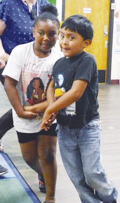 C’ianna Mbaneme, left, and James Bearshield promenade during their square dancing lesson at Nance Elementary. CDN | Christian Jacobsen