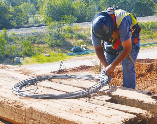 Eric Atilano unwinds the next look of metal cable to be installed as the safety line at the Interstate 40 construction over Neptune Drive. CDN | Christian Jacobsen