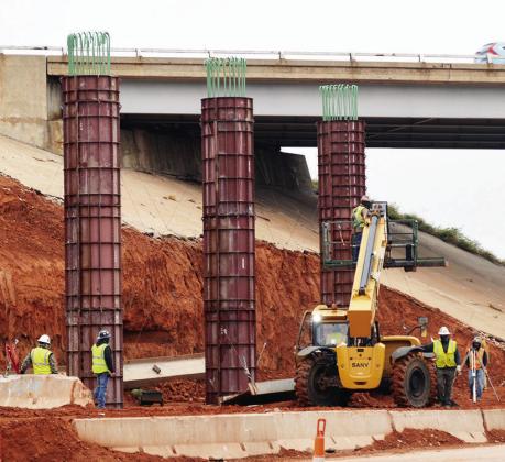 Construction crews install new support pillars for the Intestate 40 overpass Tuesday at Neptune Drive. CDN | Christian Jacobsen