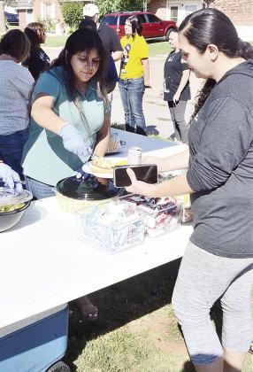 InterBank’s Maria Nolasquez, left, puts lettuce on a burger for Priscilla Lerma at the beginning of the Mission House’s barbecue Wednesday. CDN | Sam Goodwyn