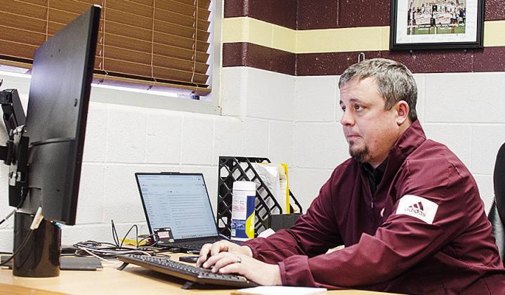 New Clinton football coach Trevor Powers works on his computer Monday as he settles into his new office. CDN | Sam Goodwyn