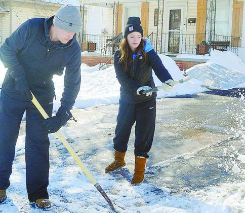 Dawson Brooks, left, and Kelcie Beals shovel the snow out from a driveway to a home Monday afternoon near downtown Clinton. CDN | Micah Ashcraft