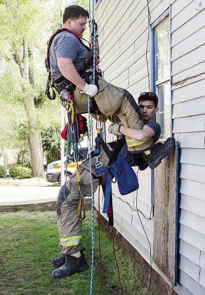 Clinton firefighter Austin Long, top, helps lower fellow firefighter Ben Switzer down during training at the Mission House.