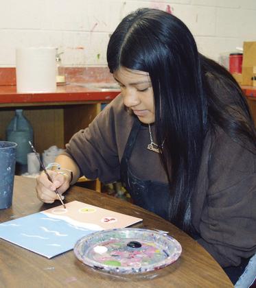 Brenda Vinaja paints shells and sand dollars onto her beach abstract art piece at Clinton High School. CDN | Christian Jacobsen
