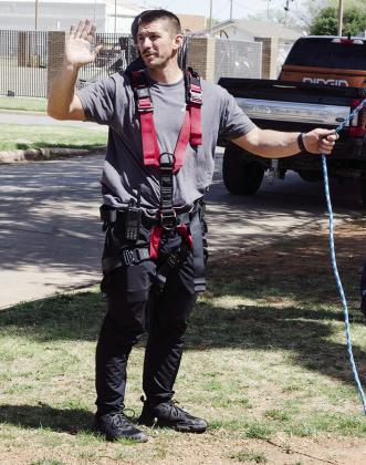 Fireman Alex Tyler yells to the aerial operator when he is in place to lower the firefighter down during training.