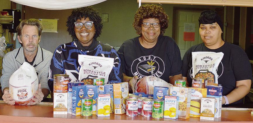 From left, Jeffrey Waffle, H.O.S.T. Ministries Pastor Wilma Jackson, Lynn Flanders, and Kendra Richardson show off the spread of food ready to be prepared ahead of the H.O.S.T. Ministries Church Christmas Free Community Meal, set for 11 a.m. to 1:30 p.m. 
