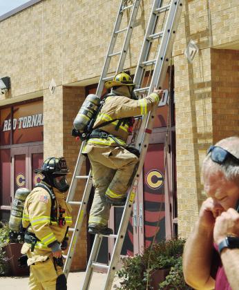 Ascending the ladder to check out the roof of the Clinton Middle School Cafeteria are firemen Austin Long and Lt. Joe Williams, as CMS Principal Gene Ray talks on the phone Monday afternoon. CDN | Staff Photo