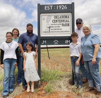 The Matz family, consisting of, from left, Kendall, Kyla, Kimber, Derek, Kellan, Perry, and Debbie Matz pose with the sign designating the Miller/Matz Farm as a historical landmark near Arapaho. CDN | Courtesy photo