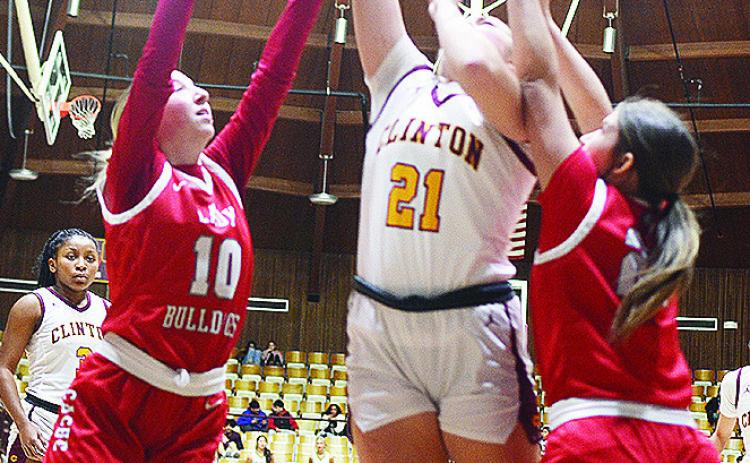 No. 21 Rhylee Rodebush goes up for a layup between two defenders during Clinton’s basketball home game Tuesday against Cache. Clinton’s Ethan Lofland takes a jump shot over a Cache defender during the Reds’ home game Tuesday against the Bulldogs.