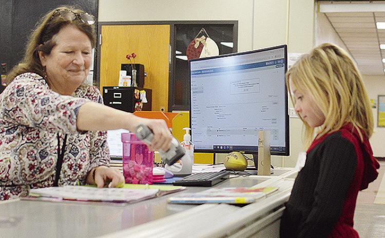 Nance Elementary School Librarian Sharon Harl, left, helps kindergartener Kezli Cox check out some new books Tuesday afternoon, on the first day of the new school semester. CDN | Micah Ashcraft