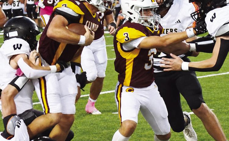 Clinton’s Easten Powell, left, fights through a couple of Woodward defenders, as Jason Lloyd, right, provides a block during the Red Tornadoes’ win over the Boomers in the Tornado Bowl. CDN | John Kinsey