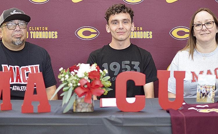 Clinton’s Xadrian Hernandez, center, celebrates Friday with his stepfather Rocky Rodriquez, left, and mother Crystal Munsey Rodriquez, right, after signing to run for Mid-America Christian University track and field, and cross country teams next year. C